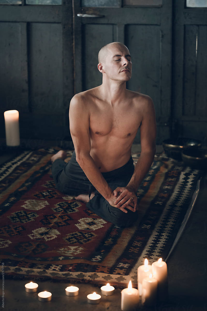 Shirtless man meditating on carpet