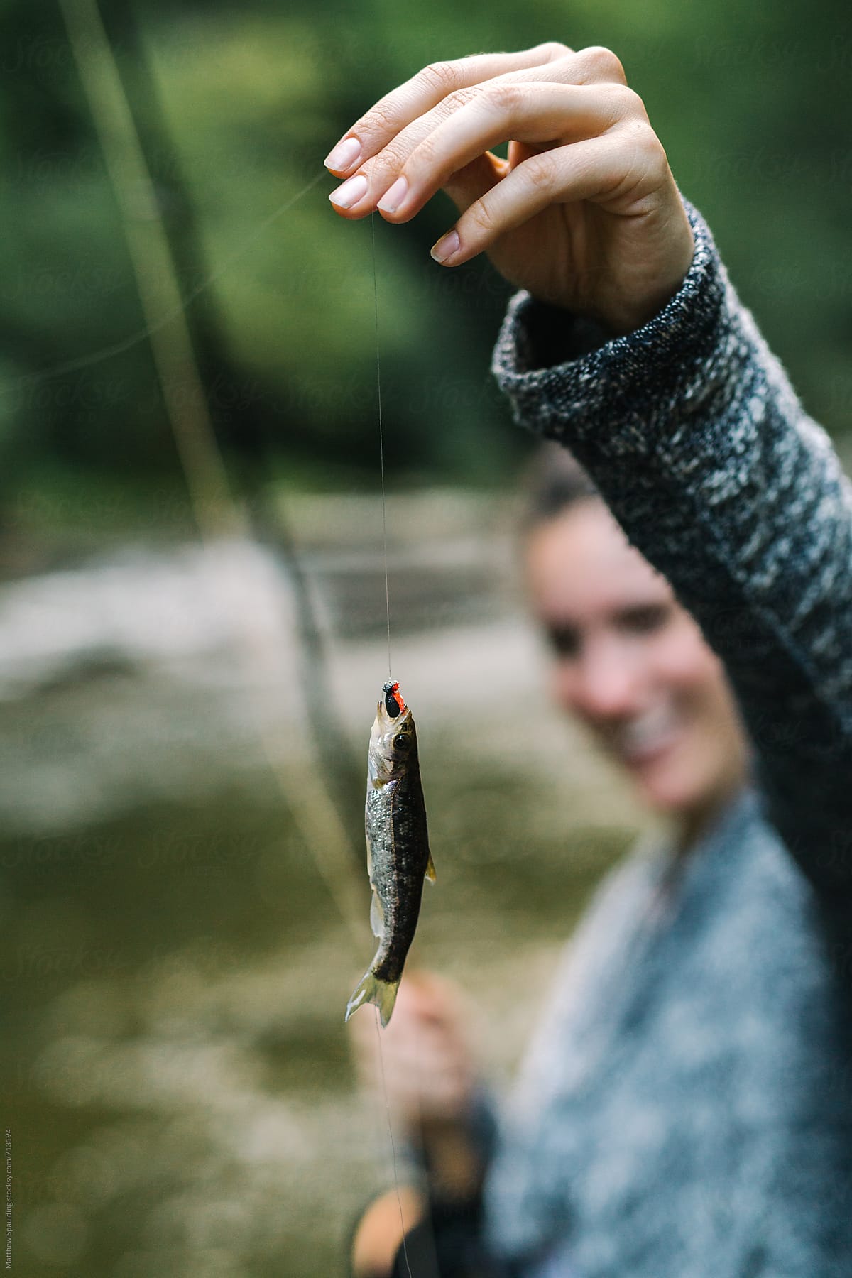 Woman Smiling With Very Small Fish Caught On Fly-fishing Line by Stocksy  Contributor Matthew Spaulding - Stocksy
