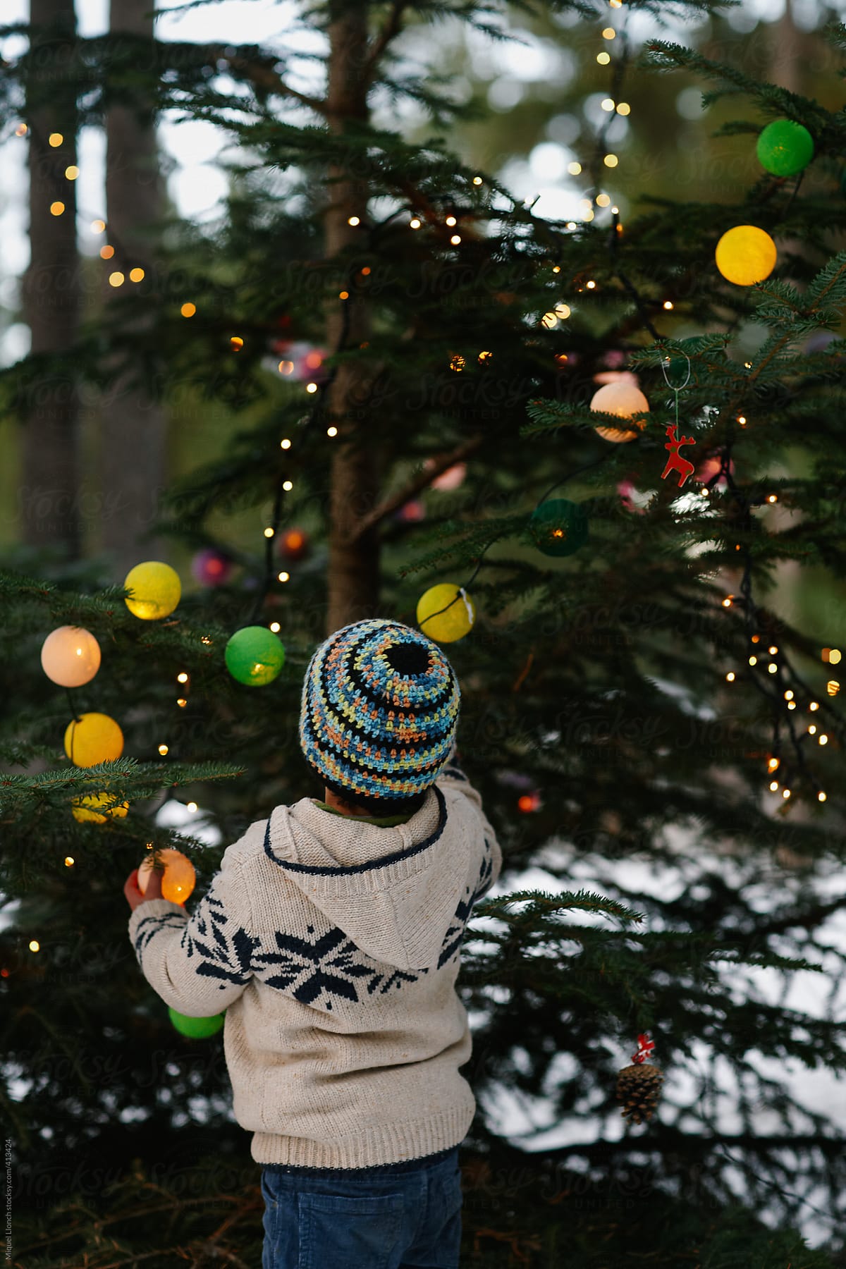 Child decorating a Christmas tree at the home yard 