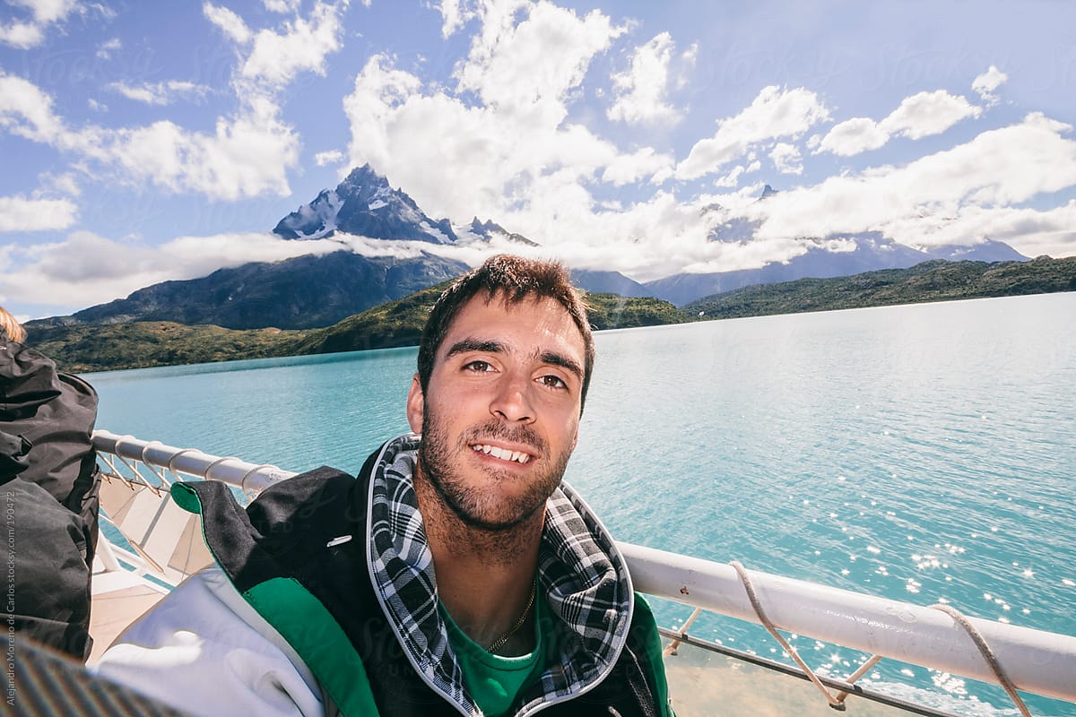 Young smiling man selfie on mountain and lake landscape while adventure travel in Patagonia