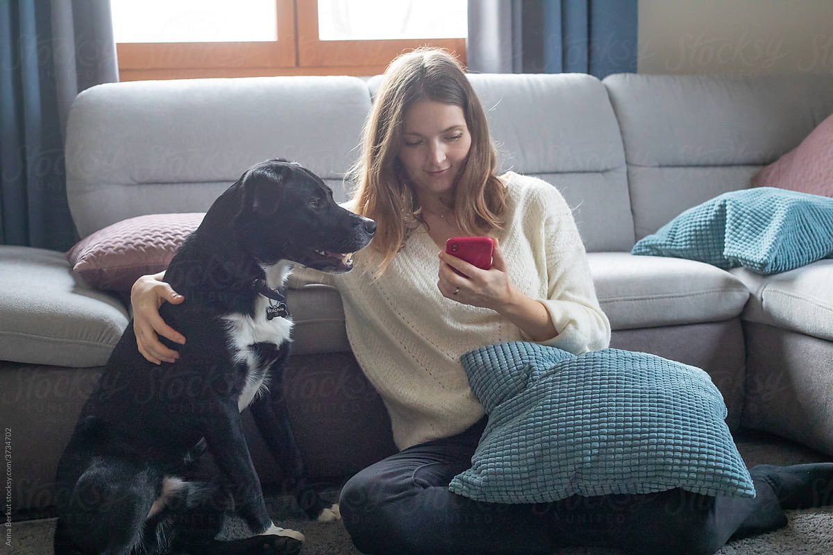 woman and dog looking at smartphone screen at home, online shopping