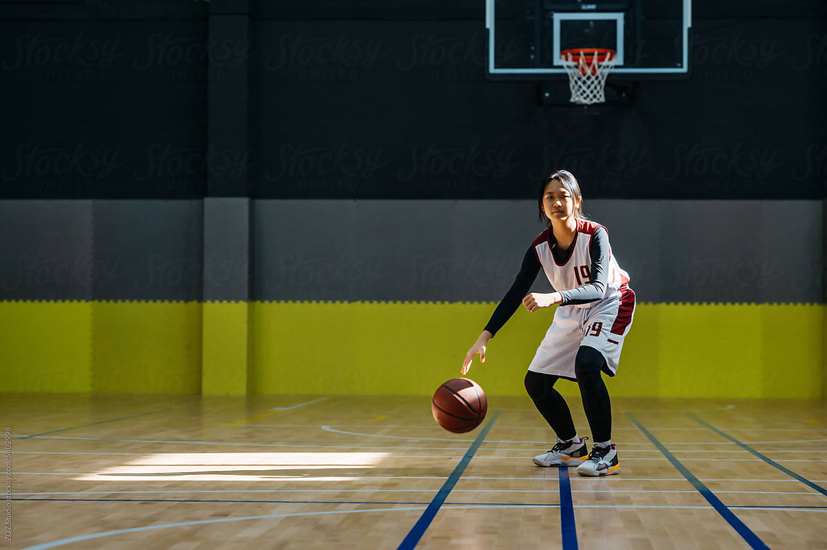 Teenage girl wearing basketball uniforms and doing drills at practice