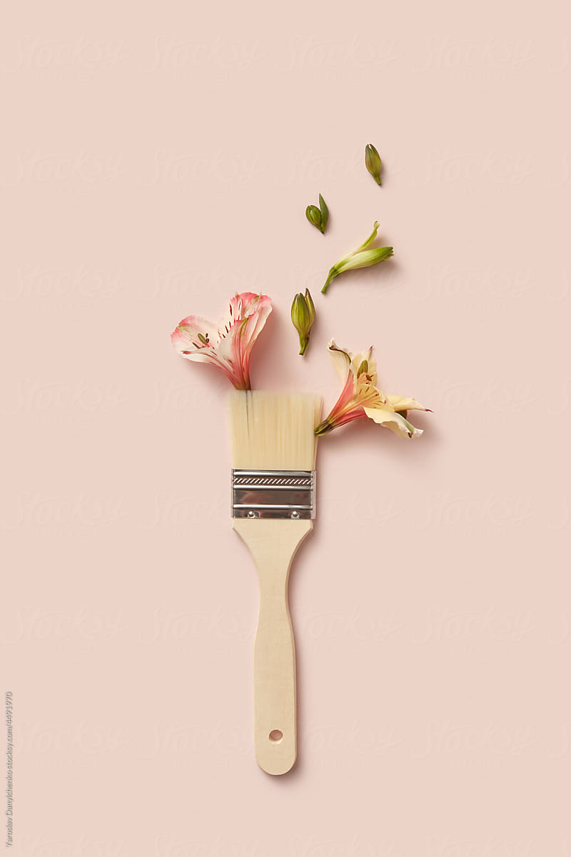 Paint brush and spring flowers on beige background