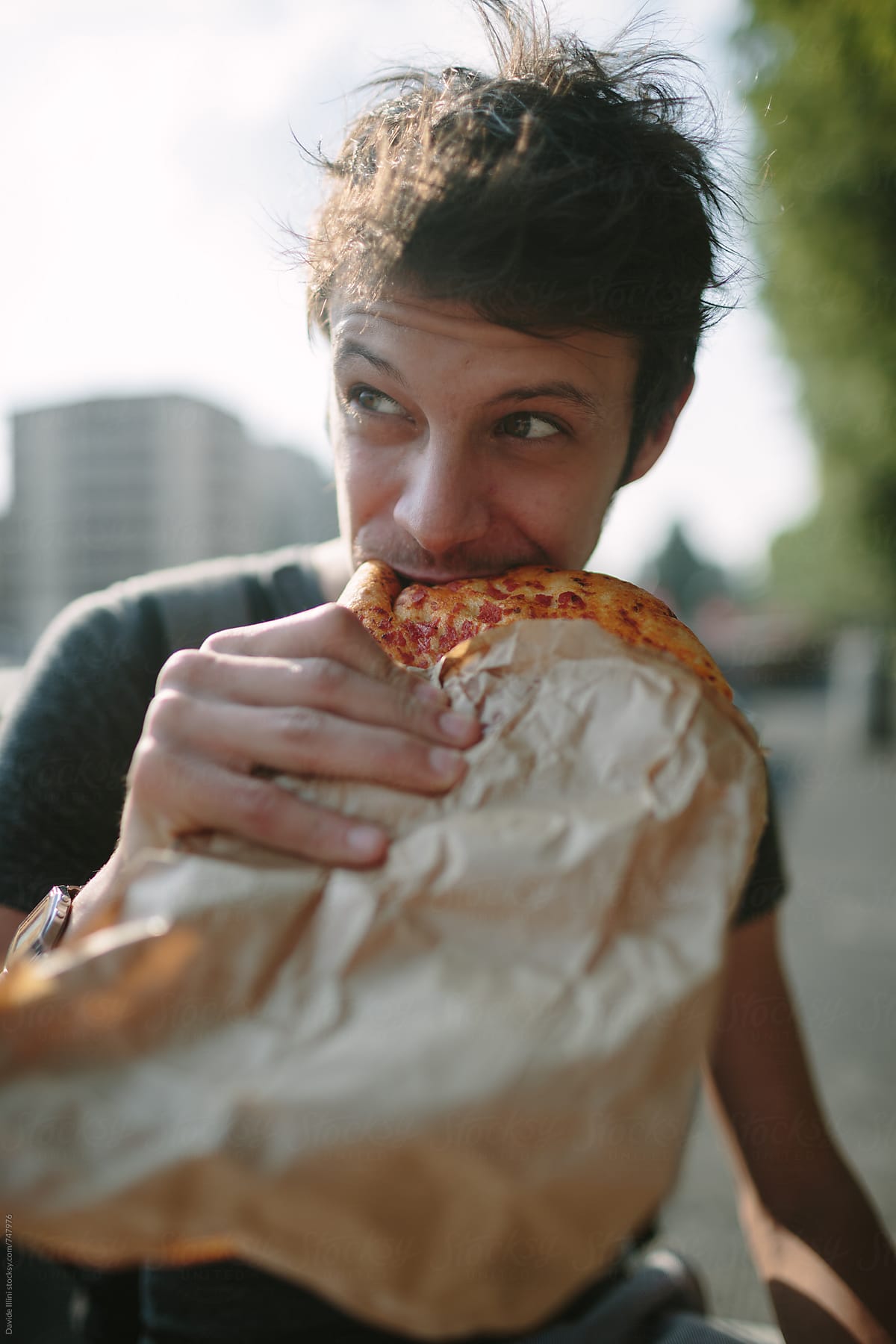 Young man eating pizza outdoors