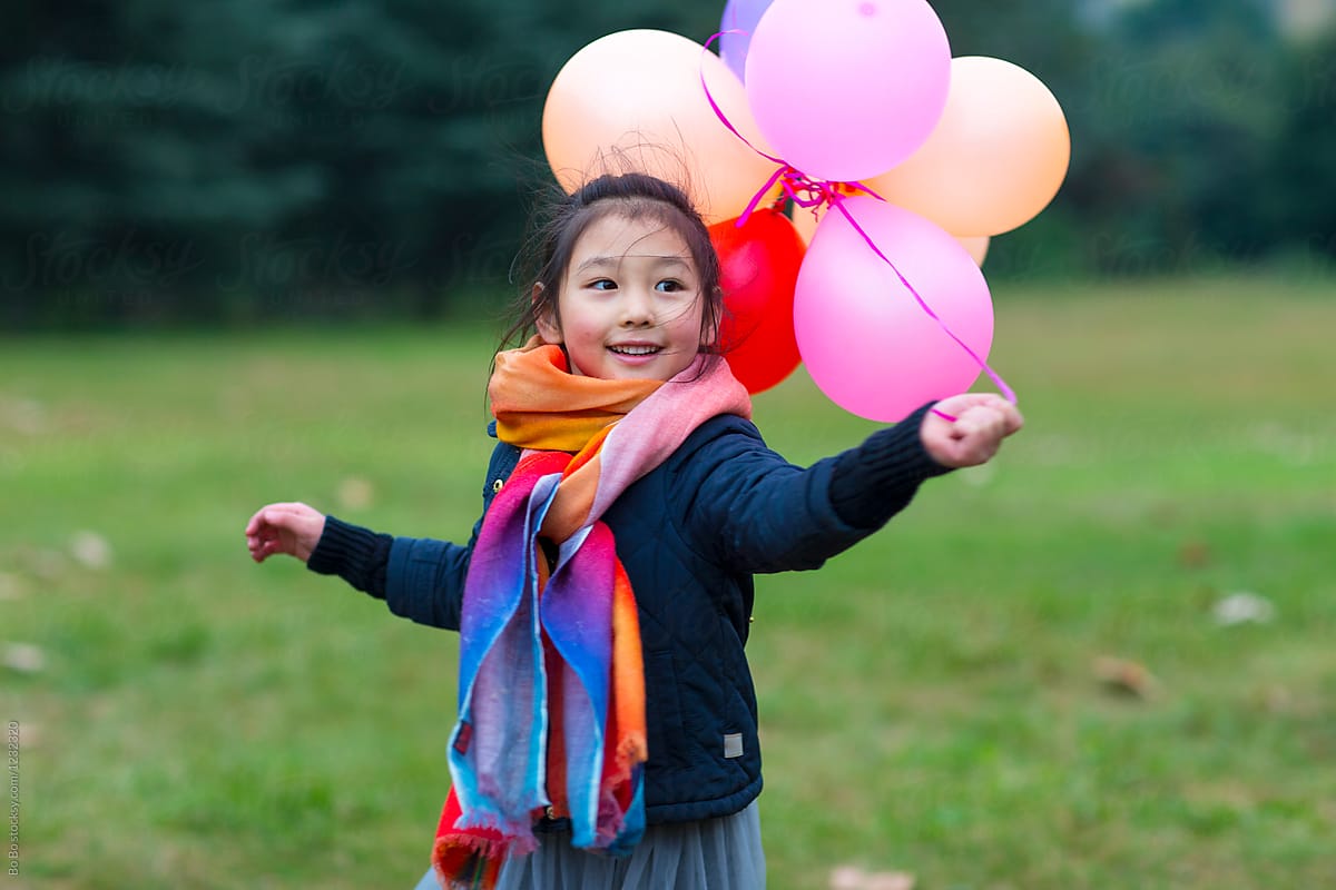 Little Girl Playing with a bunch of balloon outdoor