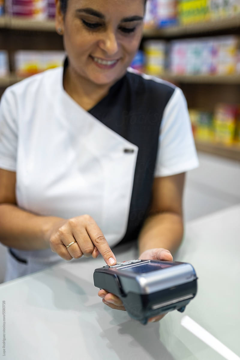 female pharmacist charging customers with card in pharmacy