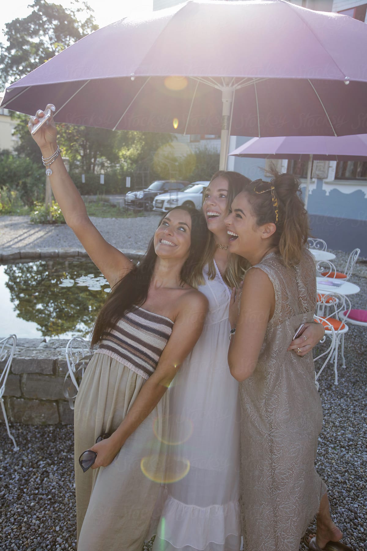 Cheerful girls taking selfie via phone in outdoor cafe