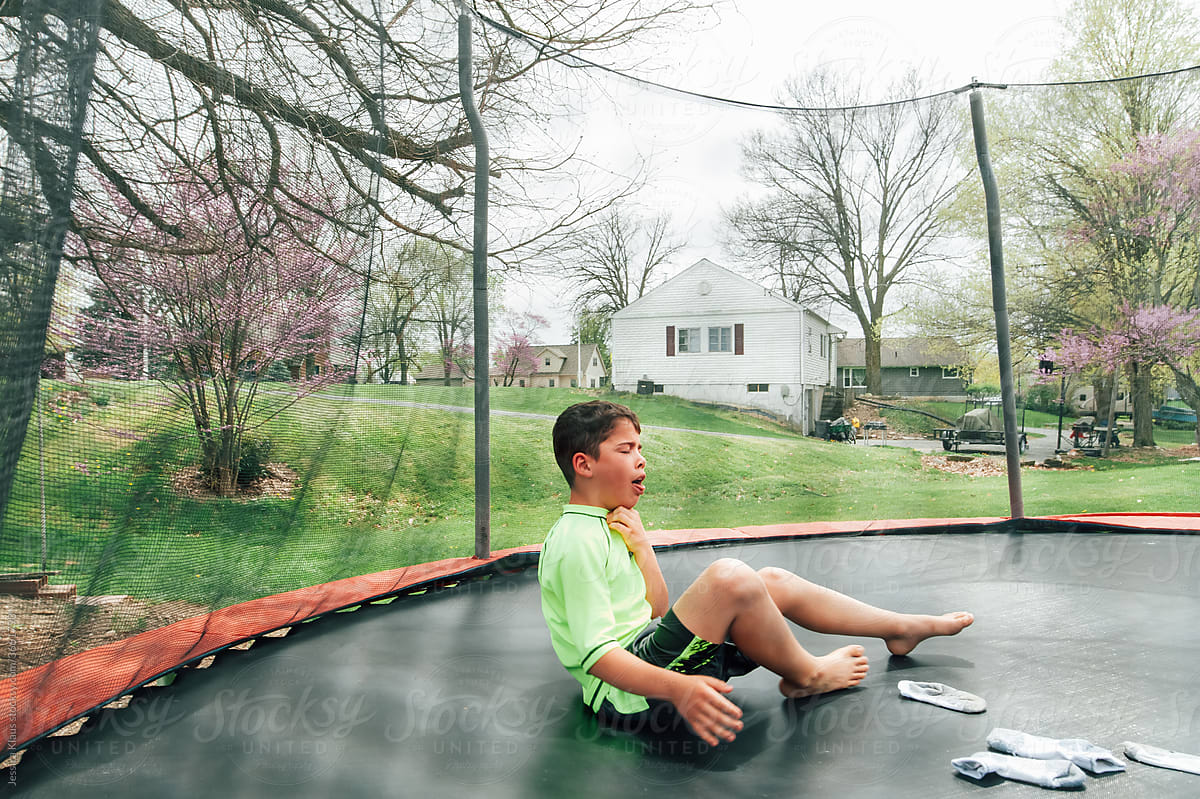 Dramatic preteen boy sitting on a trampoline.