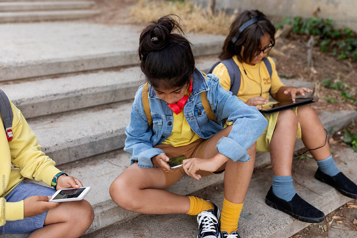 Kids sitting on the staircase using electronics