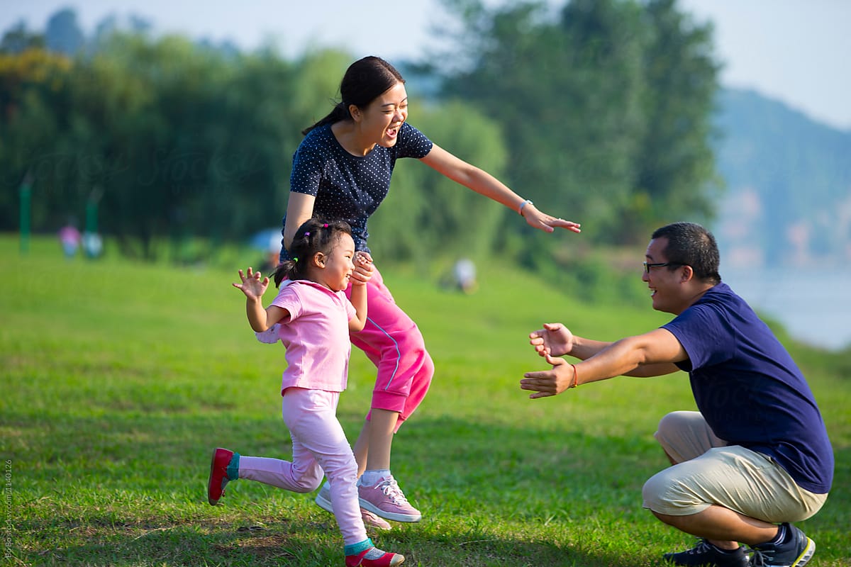 Lovely Asian Family Having Fun Together Outdoor In The Sun by Bo Bo