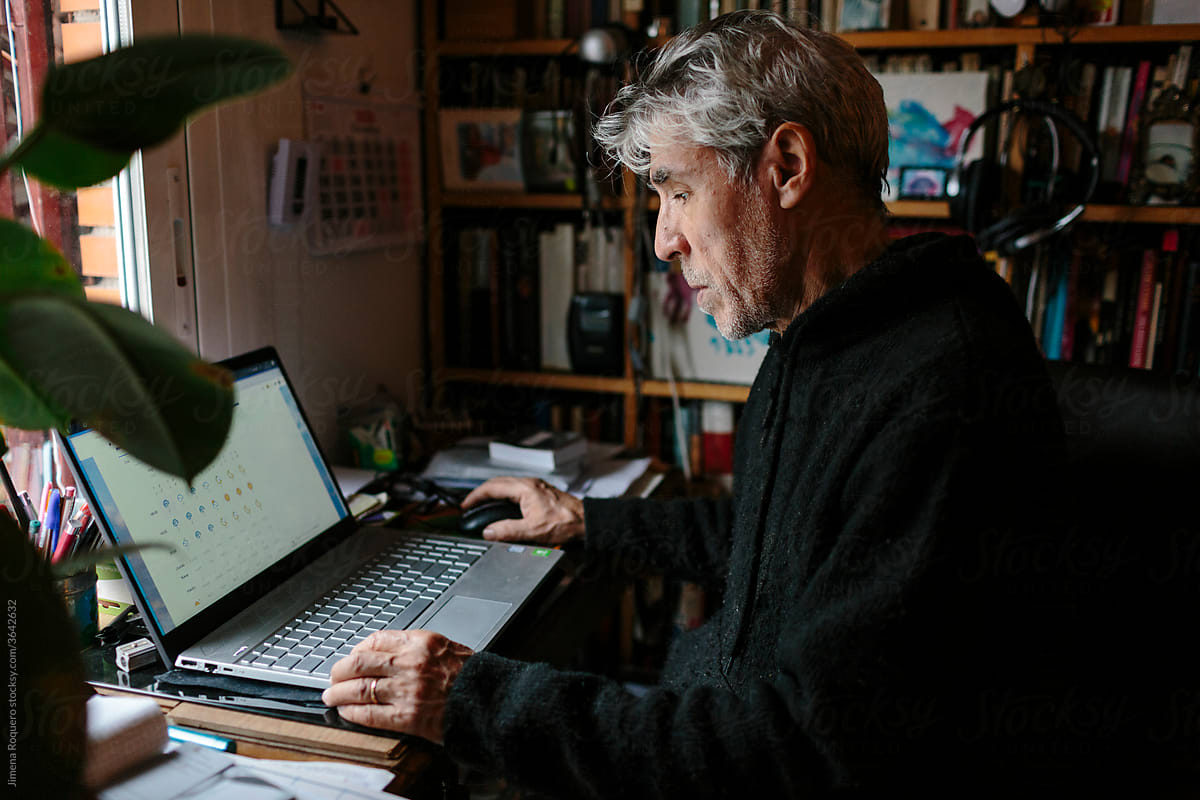Elderly man checking the weather forecast on his laptop at home