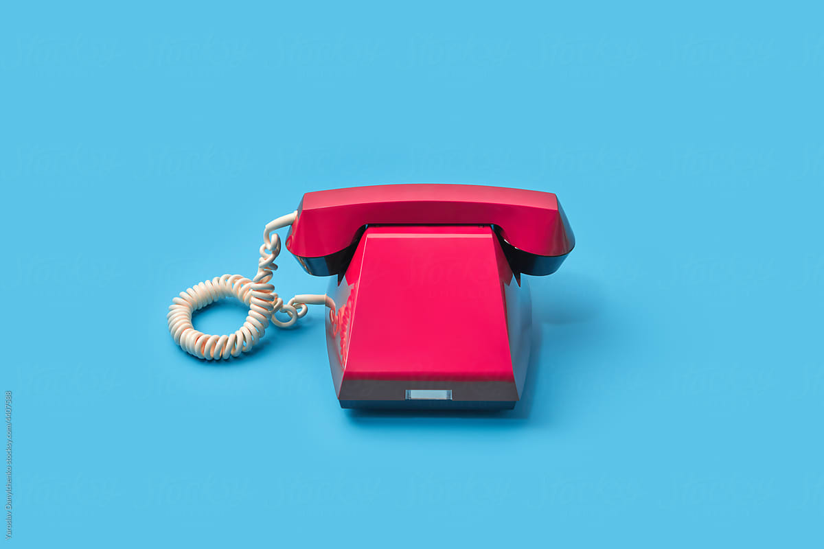 Old fashioned red telephone over light blue background
