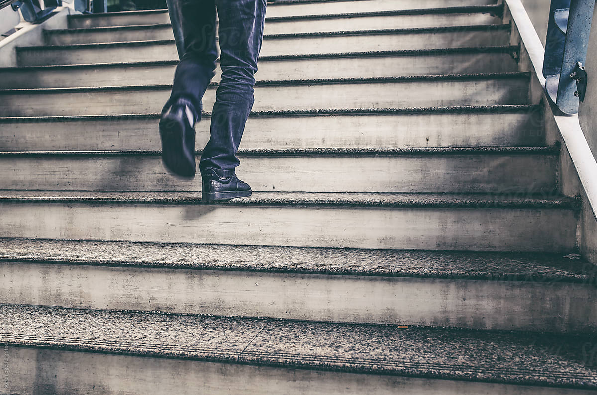 Closeup of mans black jeans and shoes walking up a stair case in
