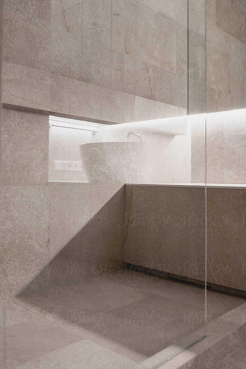 Interior of illuminated modern bathroom with tiled walls