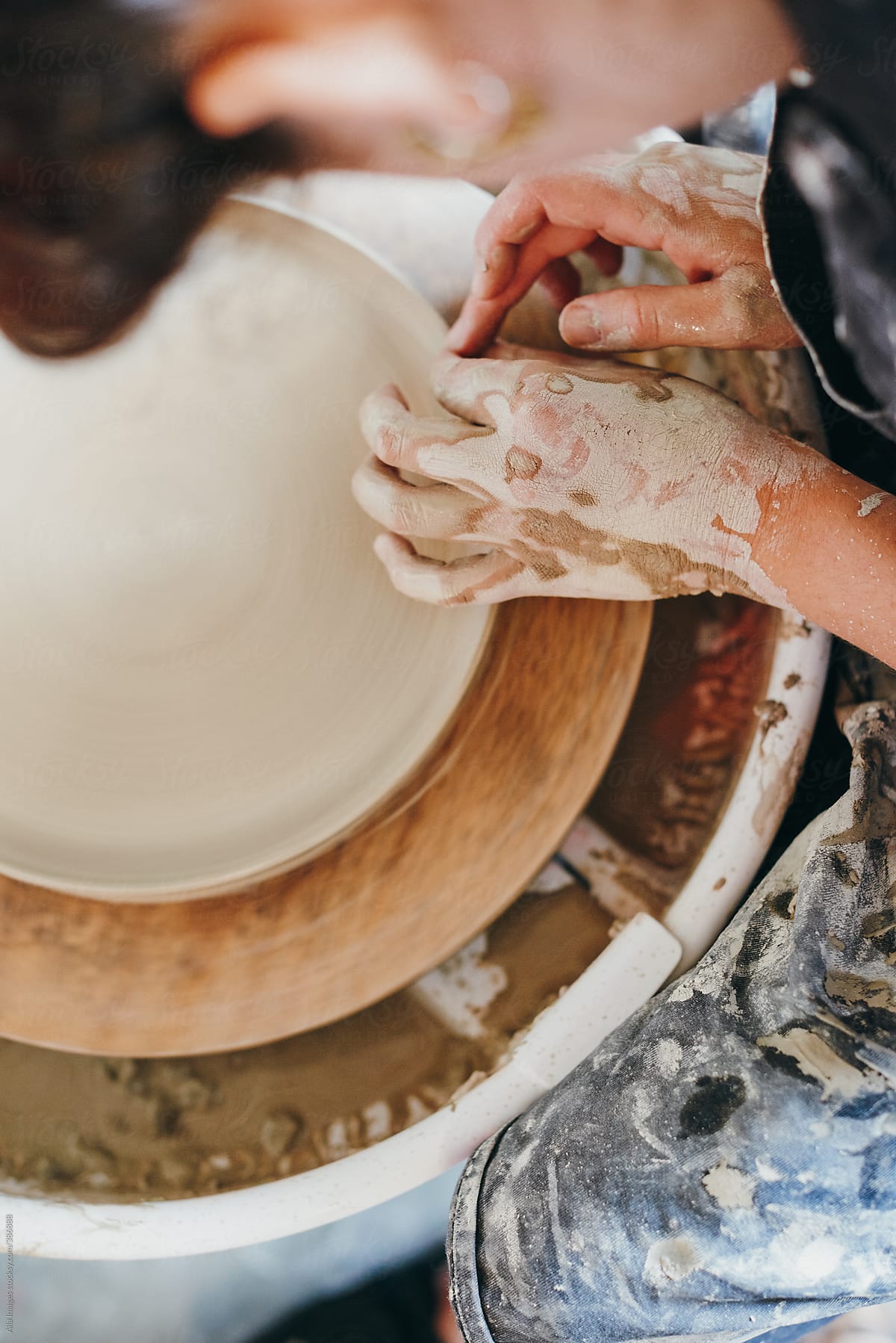 Woman making a ceramic plate on a turning wheel