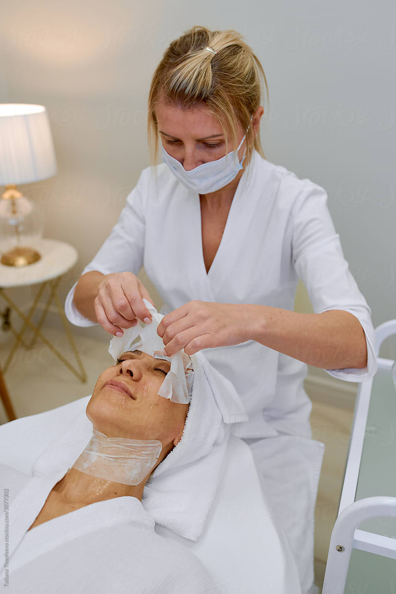 Cosmetologist doing face massage adult woman patient in beauty salon