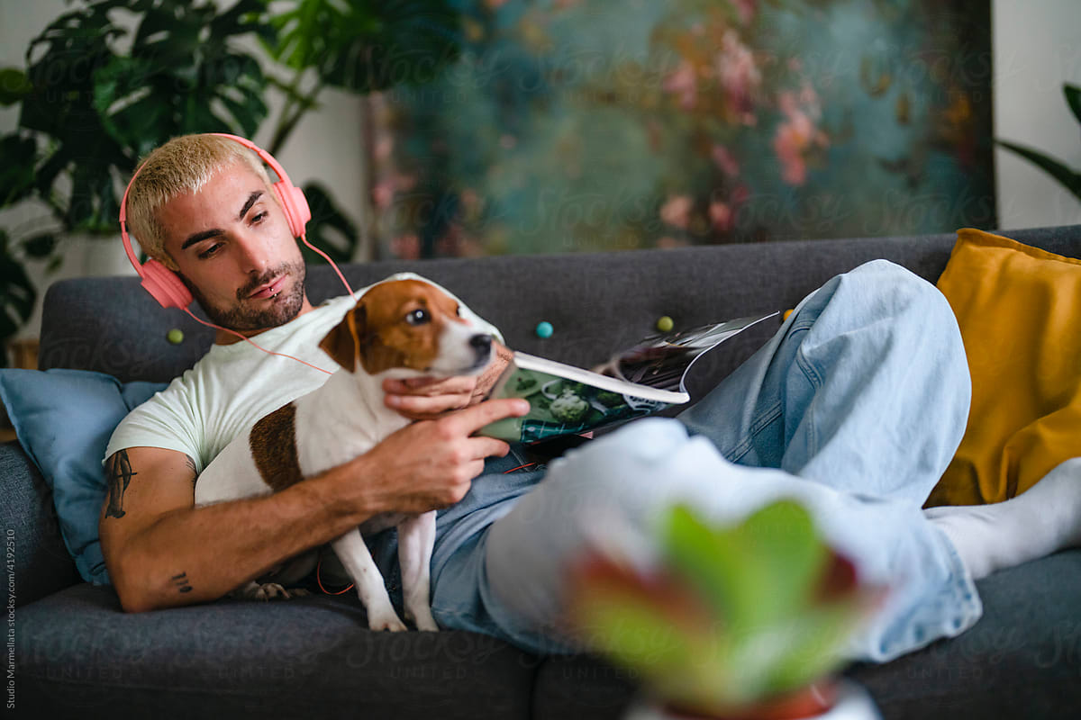 Dog owner reading magazine on sofa
