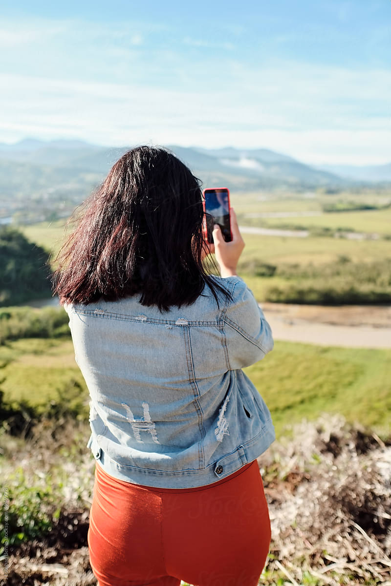 View from behind of a woman taking a picture with her phone