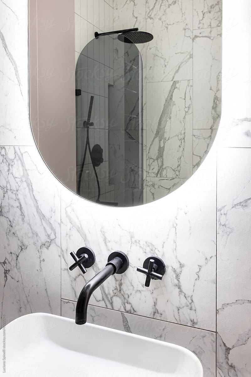 Rounded mirror in a toilet with a pink and grey shower