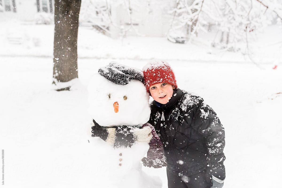 little boy standing byes snowman