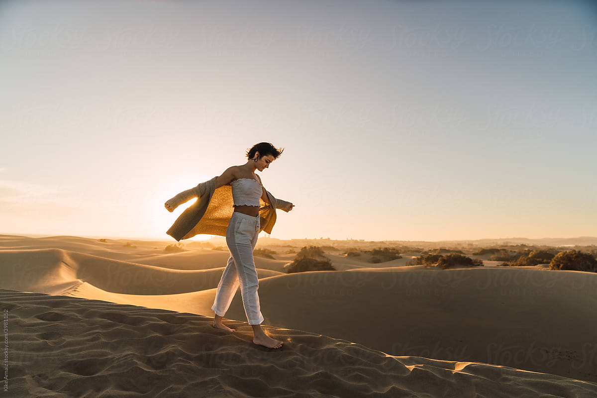 Woman standing on sand land and blue sky at sunset