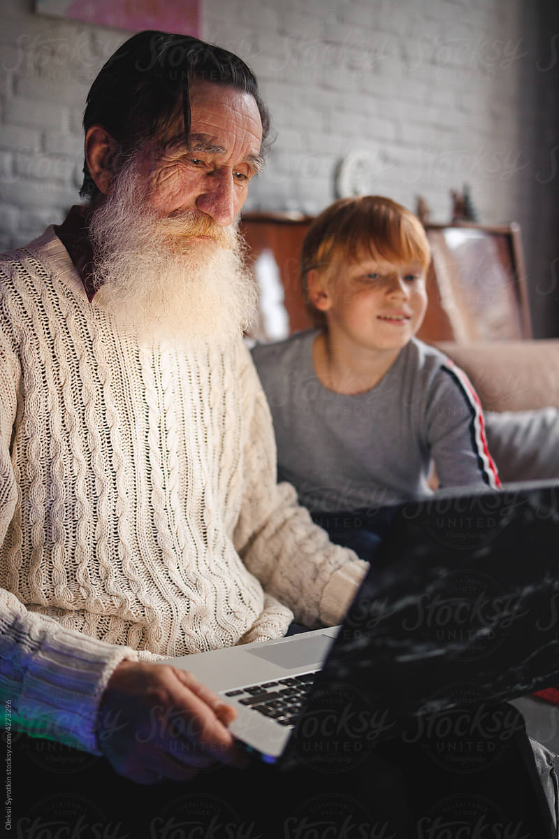 Busy grandfather watching something on laptop with boy