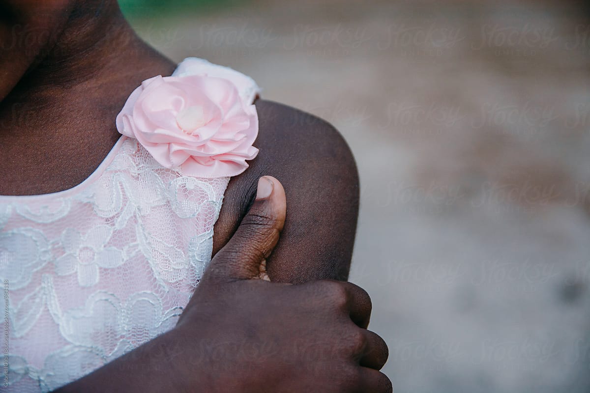 Hand and shoulder of an African American girl in pink dress