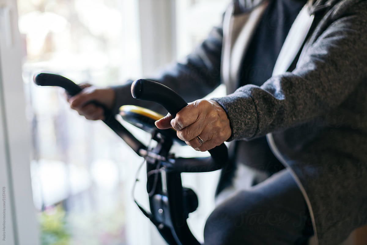 Unrecognizable senior woman exercising on cycling machine