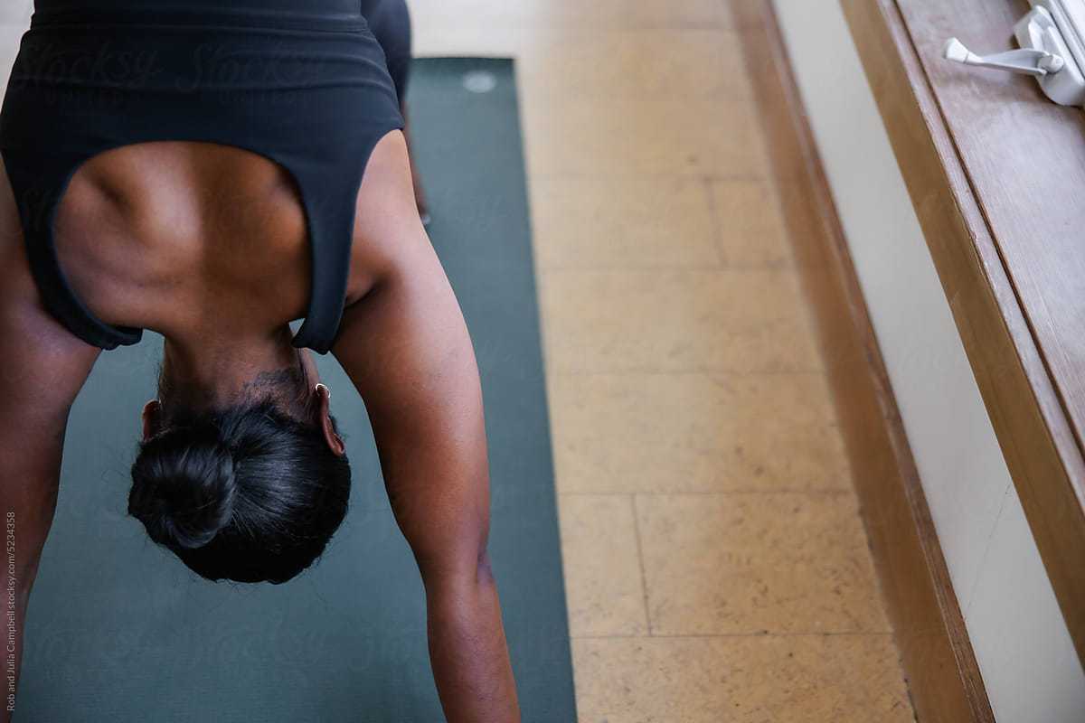 Woman in downward dog pose during yoga studio class.