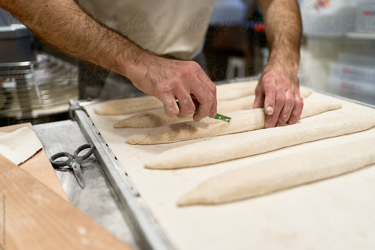 Crop man making baguettes from dough