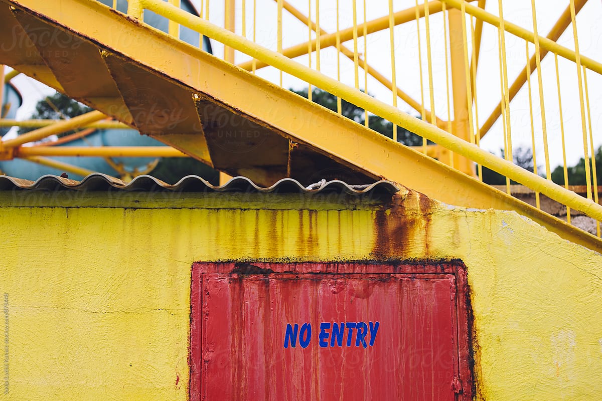 No entry sign in blue colour on red door and yellow wall
