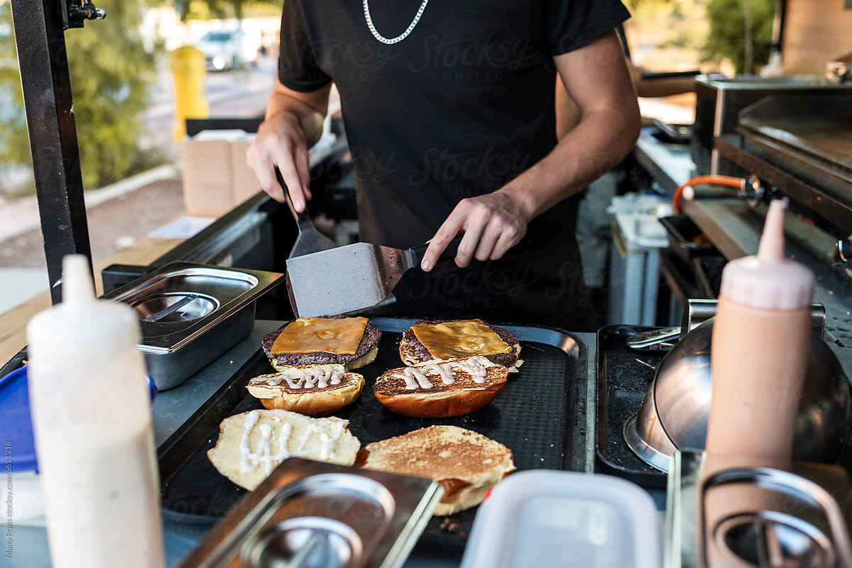 Chef plating cheese burgers in a small business food truck