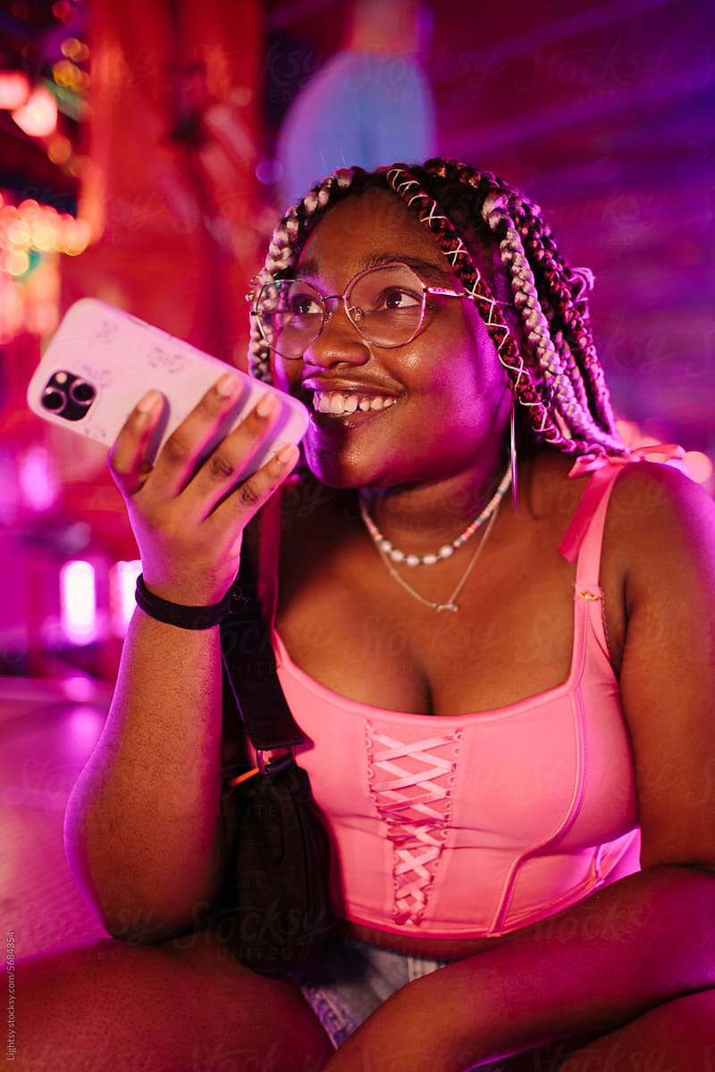 Young African American woman sending voice notes with smartphone