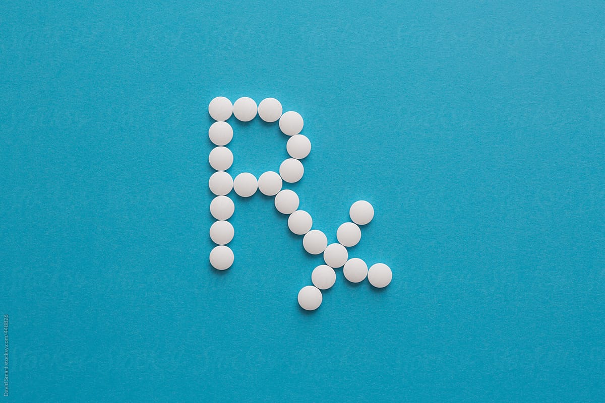 Prescription symbol Rx made of white tablets on a blue