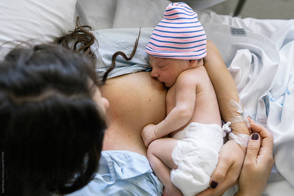 Young woman Breastfeeding Newborn In Hospital