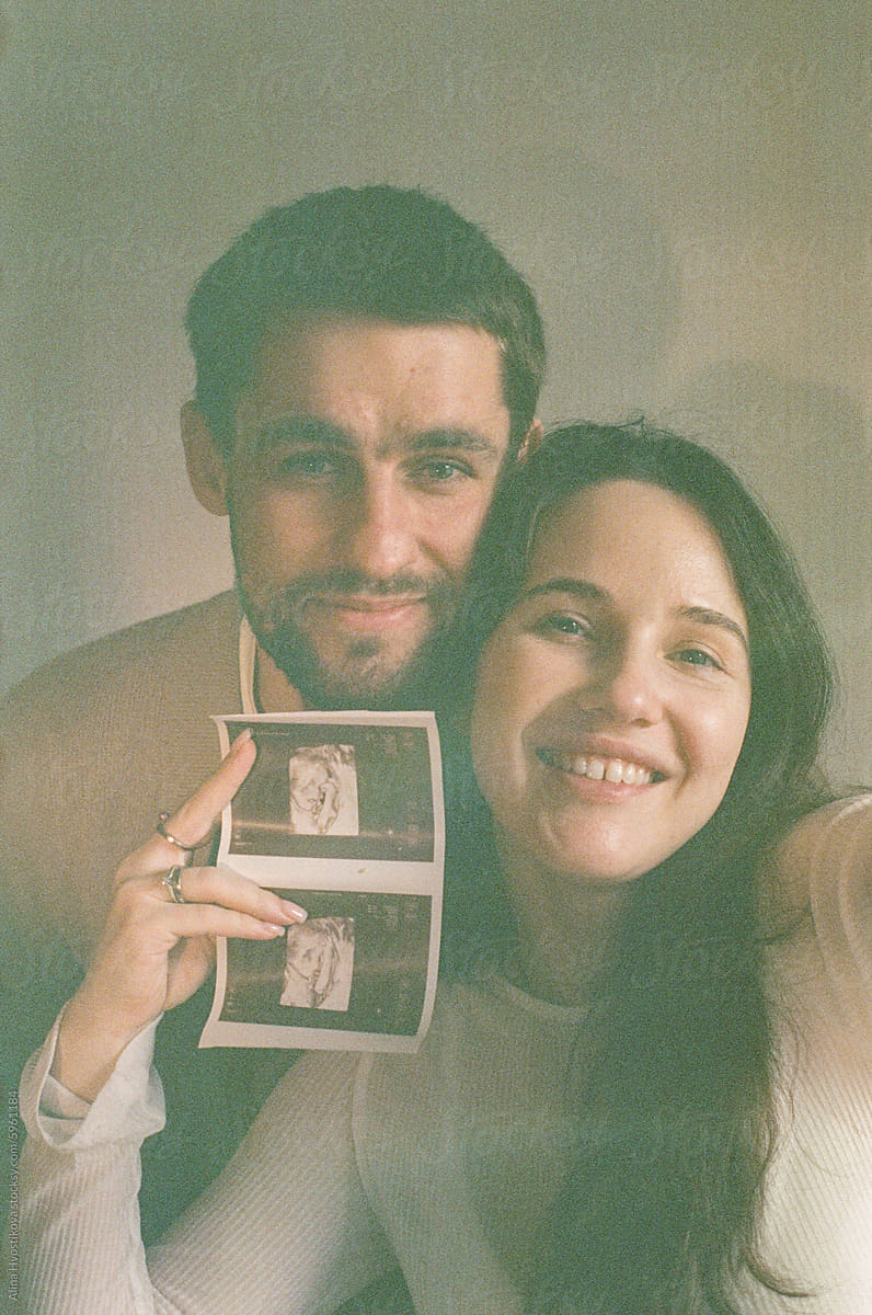Cheerful couple taking selfie with ultrasound image