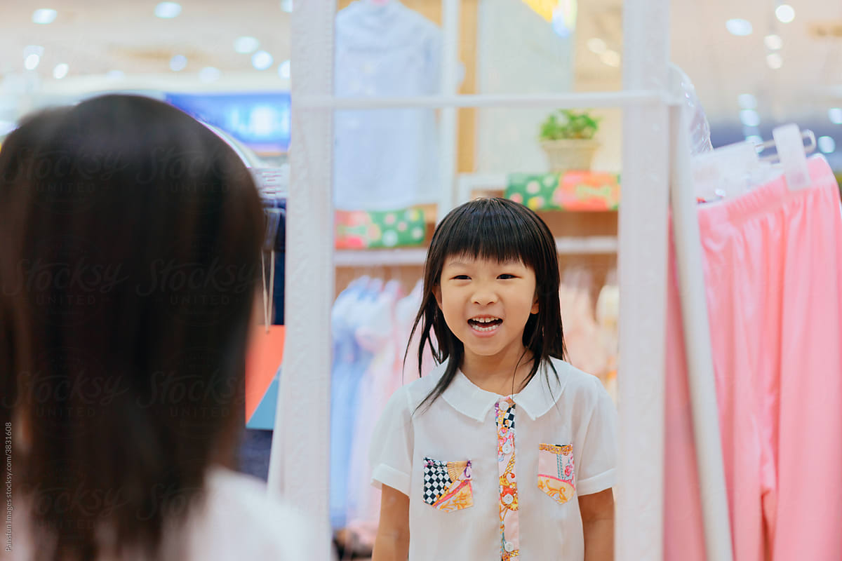 Little girl trying on clothes in front of mirror
