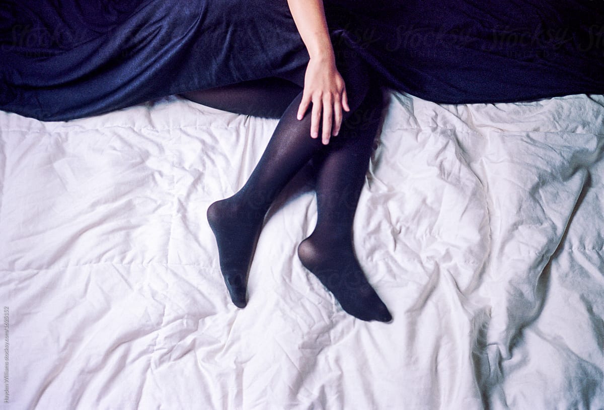 Woman lying in bed wearing black stockings