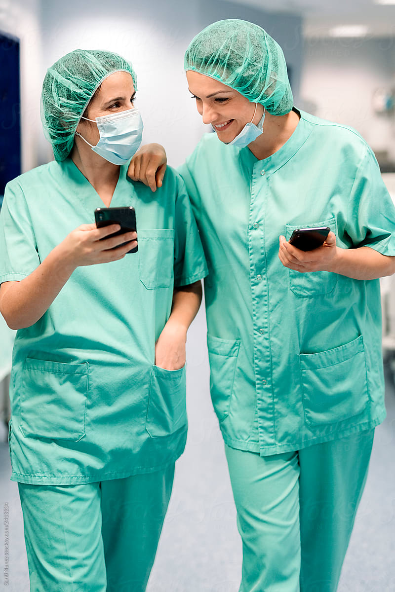 Female doctors in uniforms and masks using smartphones