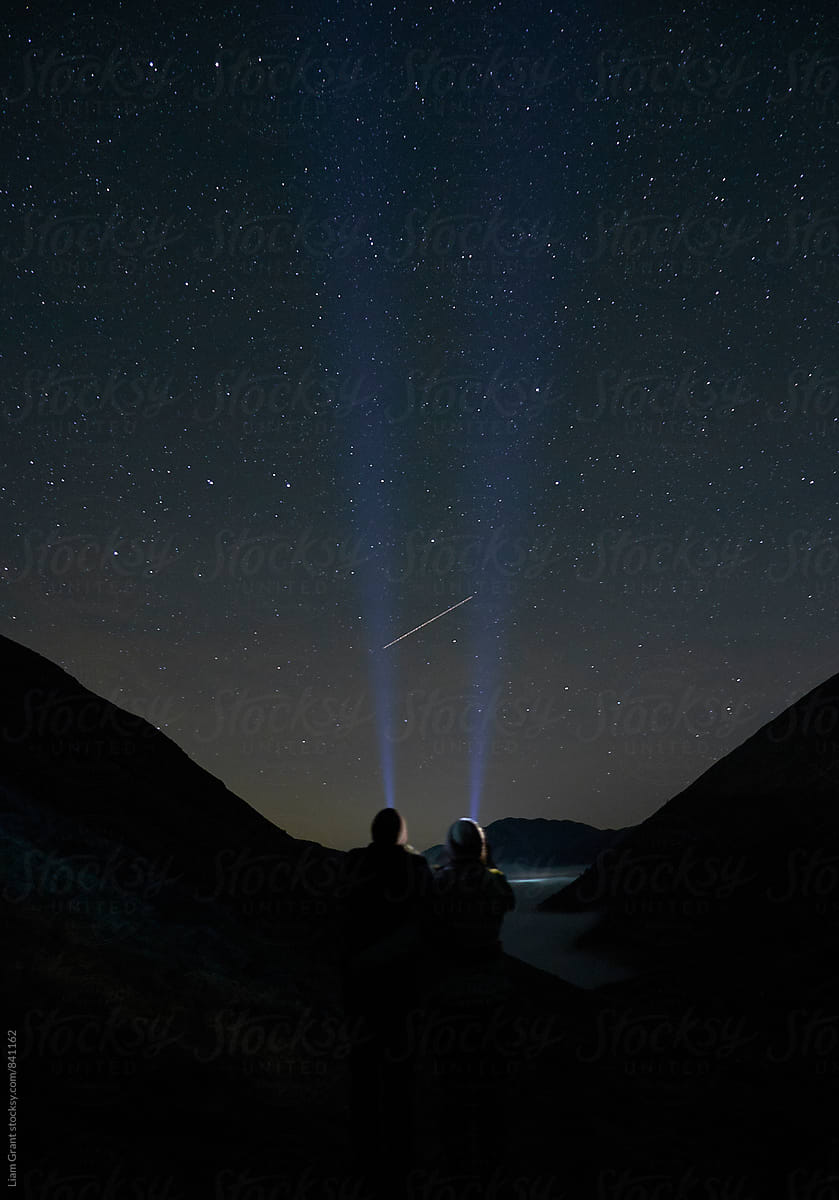Young couple watching shooting stars in the mountains. Cumbria, UK.