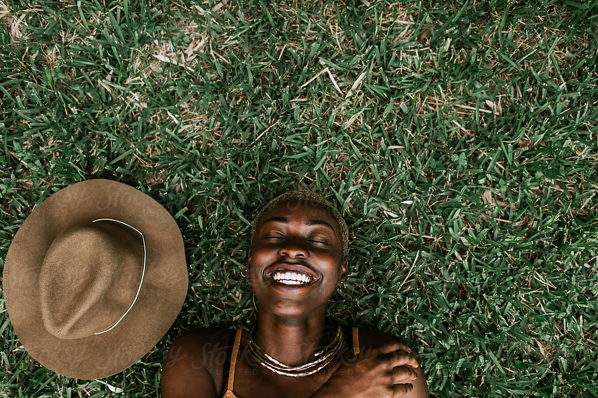 Portrait Of A Beautiful Black Woman Laying Down In The Grass. by
