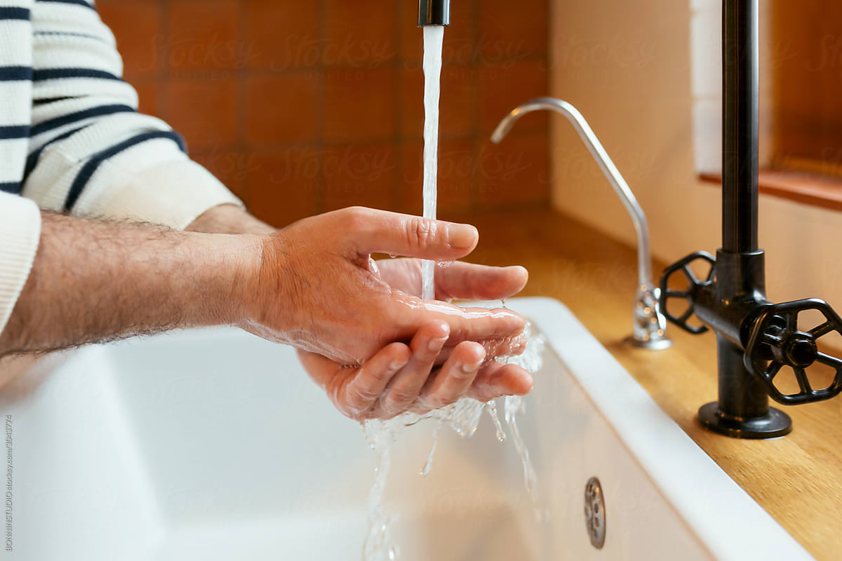 Crop man washing hands under clean water