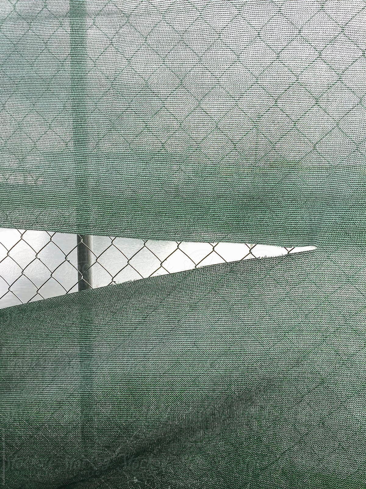 Torn green fabric covering chain-link fence