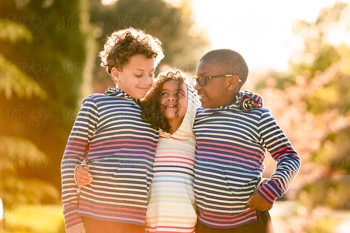 Three children with arms around each other laughing