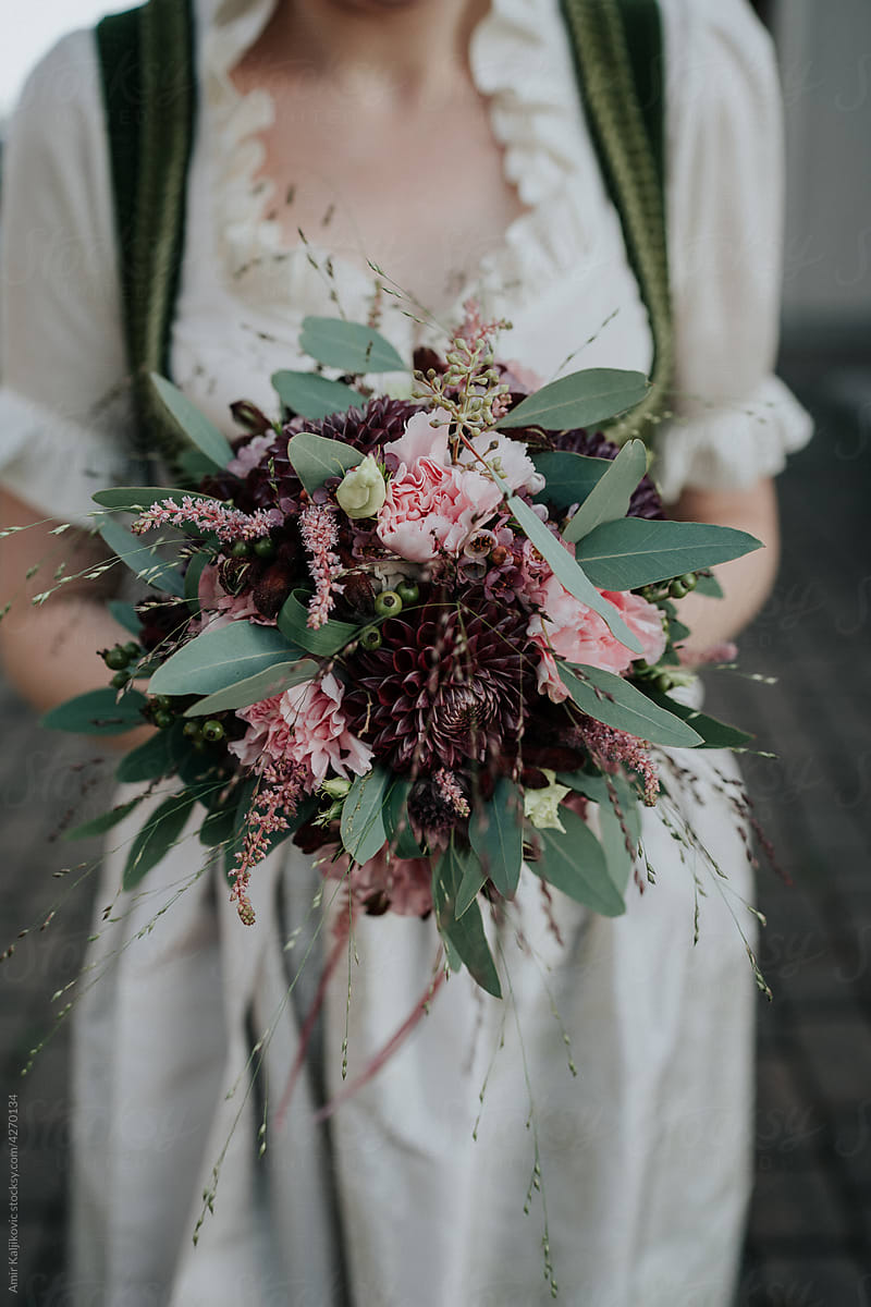 Bride holding a bouquet of pink and maroon flowers