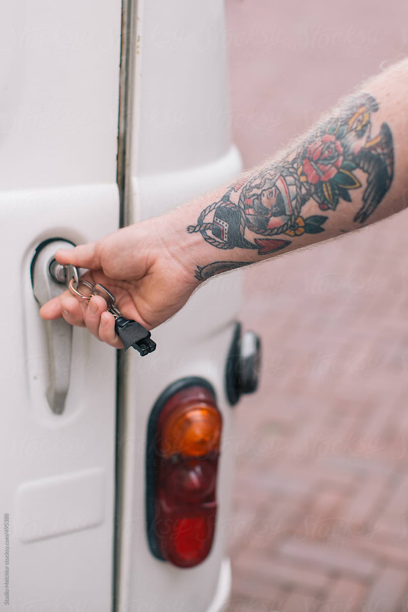 Tat toot mens arm is locking a car backdoor