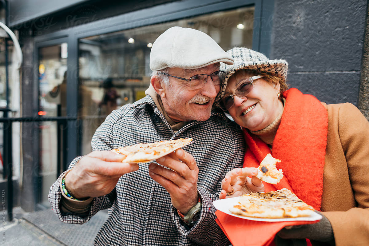 Senior Couple Eating Pizza in City