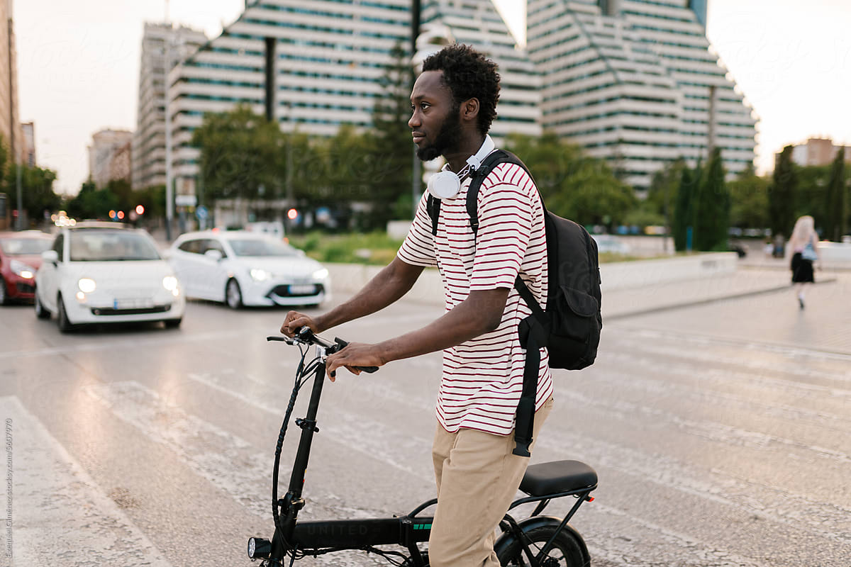 Cool black guy rolling bicycle on crosswalk in city