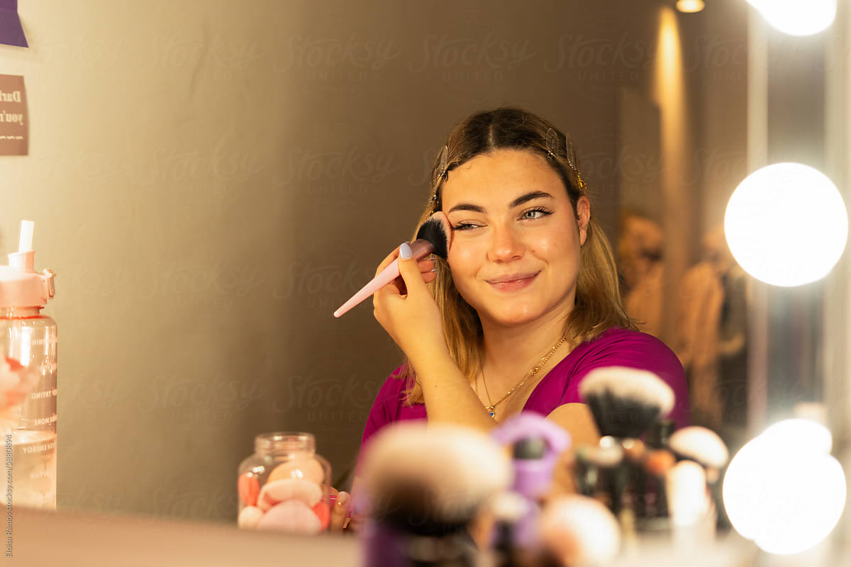 playful Woman Applying Blush in a vanity mirror