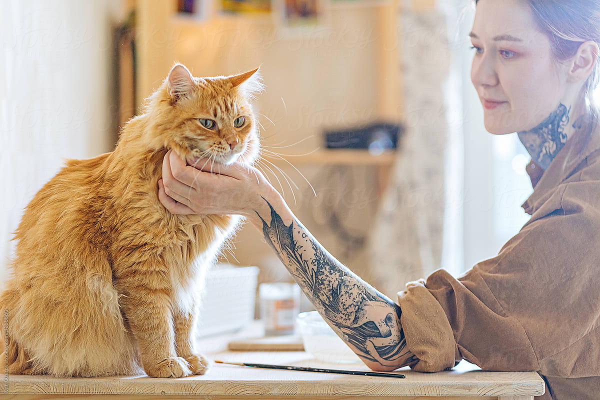 tattooed girl stroking her ginger cat